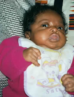 Isabelle relaxing on the couch in pj's and bib after a meal.